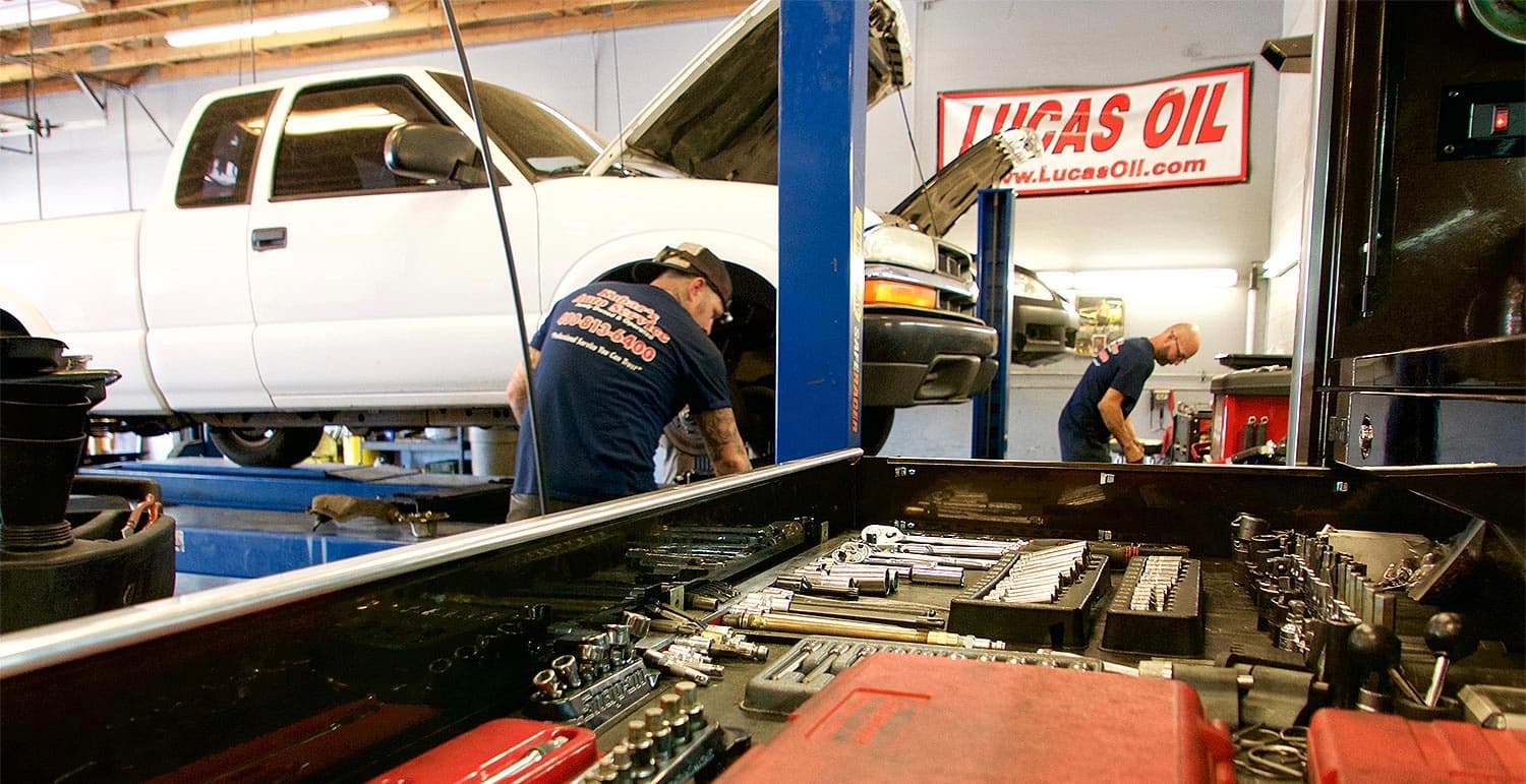 Technician working on a truck with Lucas Oil branding visible